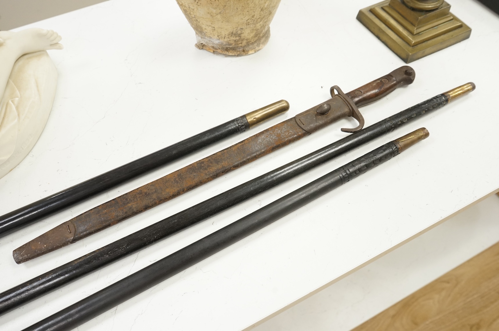 Three early 20th century Indonesian bone overlaid sword sticks and a bayonet, largest 92cm in length